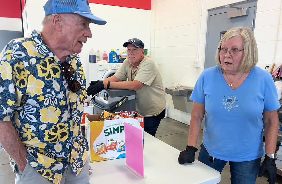 Bob Sherwood, (l) talks with Peggy Gould (r) as Casey Berens (center) oversees hot dog distribution