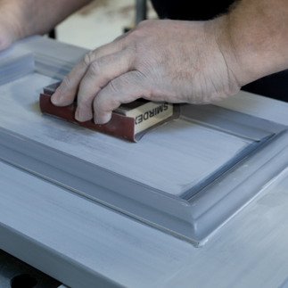  Close-up of craftsman refining cabinetry panel with sanding block