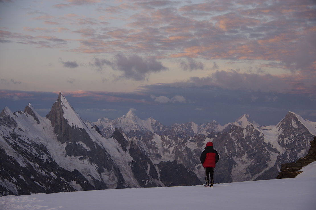 A trekker looks at Laila Peak from the top of Gondogoro La