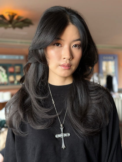 Smiling Asian woman in black top, against a living room   background