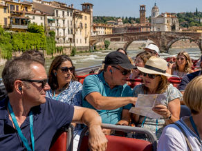 Un gruppo di turisti scende dal bus turistico parcheggiato a Piazza Bra, pronti a scoprire le bellezze di Verona.