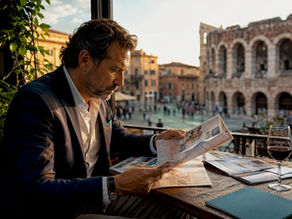 Un uomo seduto nella hall di un hotel a Verona mentre valuta le diverse strutture dove soggiornare.