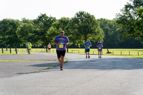 Running Strong member running in race at park.