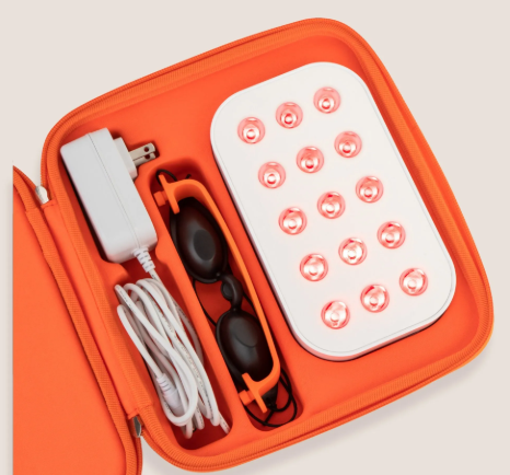 Portable red light therapy device kit featuring a light panel, protective goggles, and power adapter neatly organized in an orange case.