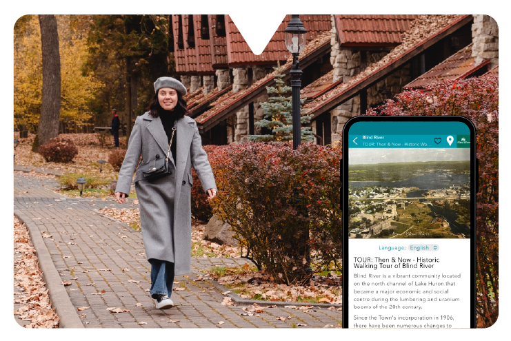 Woman in gray coat and beret walks on a brick path in a park with autumn trees. Nearby, a phone is open to the Driftscape museum tour app displaying a historical walking tour.