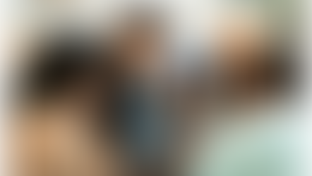 Four people gather around a smartphone displaying the Driftscape digital tourism app, focused and engaged. They are indoors with a blurred background and casual attire.