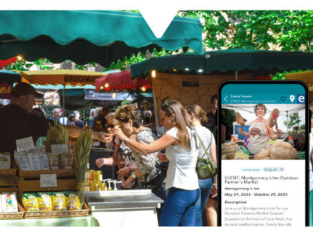 People browse a colorful outdoor farmer's market. A phone screen displays event details, part of the Driftscape app.