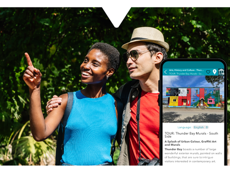 Man and woman outdoors under sunlight. Man holds a smartphone showing Driftscape tourism platform.