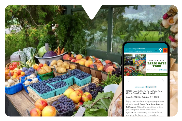 Colorful farm produce on a wooden table, including apples, grapes, and potatoes. A smartphone with the Driftscape interactive tour guide app displays "North Perth Farm Gate Tour."
