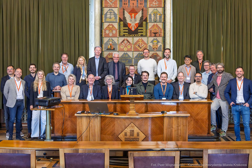 Groep Nederlandse fietsprofessionals in een raadszaal in Kraków met houten lambrisering, groene gordijnen en een kleurrijk wandtapijt.