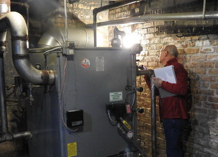 Volunteer Jim Cavallo inspects a furnace on an energy audit.