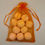 Thumbnail: 10 Orange Chill Pills, (mini bath bombs) inside the included organza bag in front of tan background