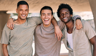 Three young men with arms around each other smiling for a photo
