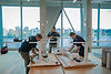 Three men assembling white office desks by a window view.