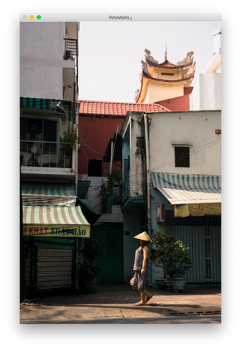 A Woman In A Yellow Hat Walking Down A Street by Pete Walls