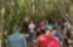 A crowd of community members gathers in the creekbed under the willows for a trout talk with Dr. Robert Leidy.