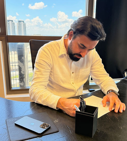 Diego Camargo, Homem de camisa branca assinando documentos em uma mesa de escritório.