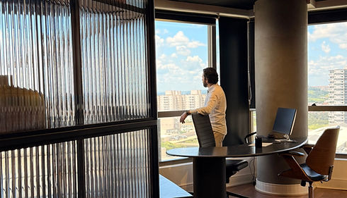 Homem em escritório moderno observando a cidade pela janela