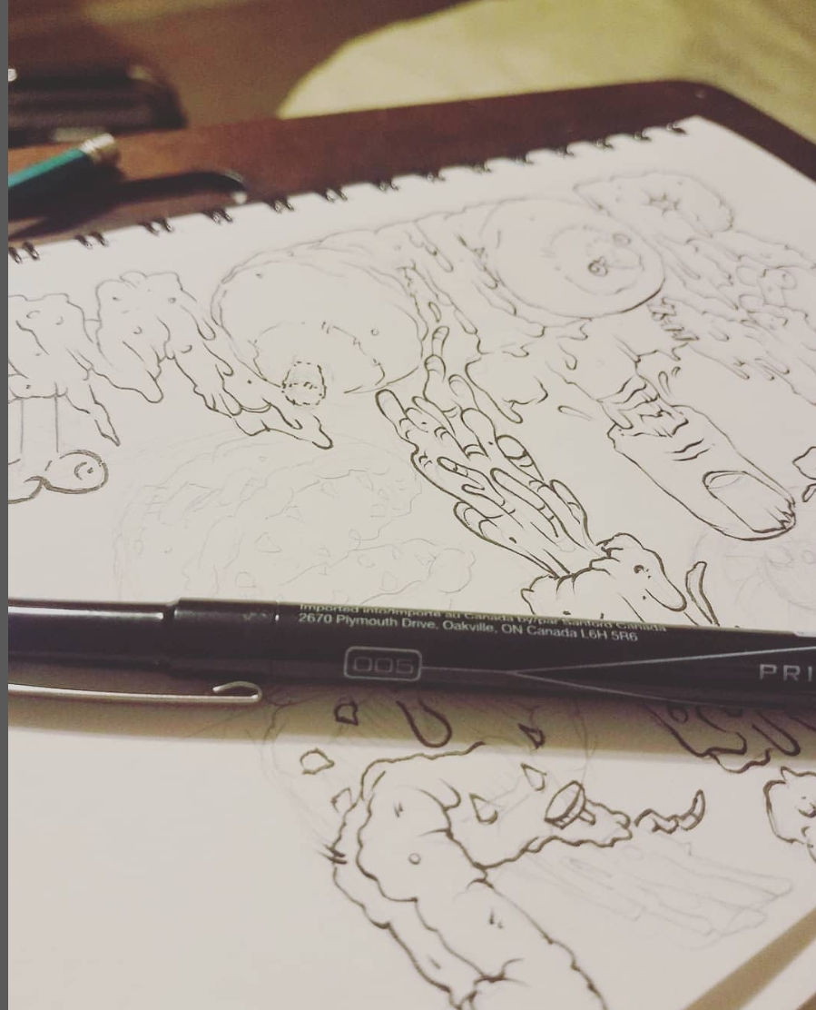 a pen laying on a drawing pad with a black and white drawing on the paper