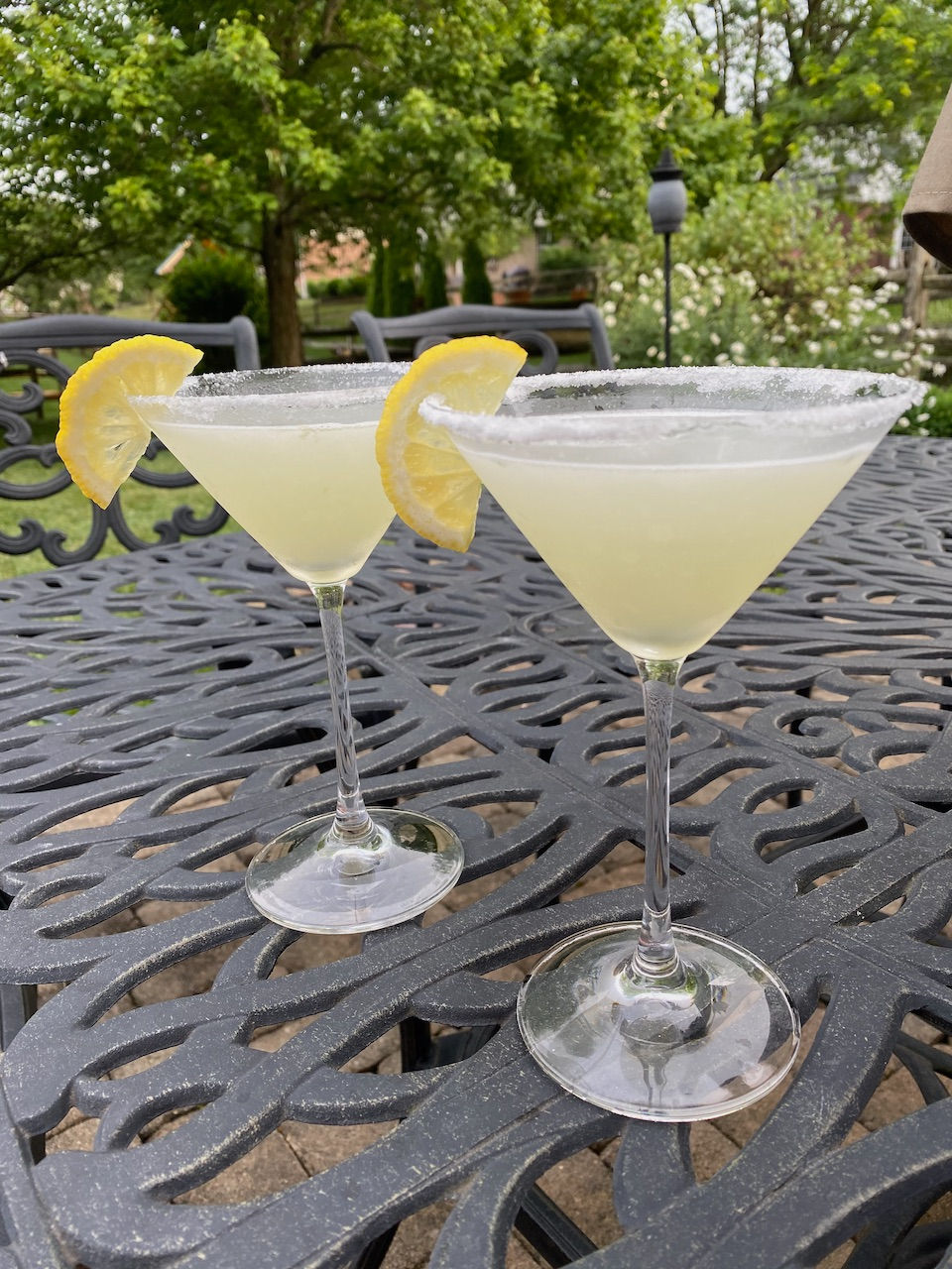 Two lemon drop martinis sitting on a patio table.