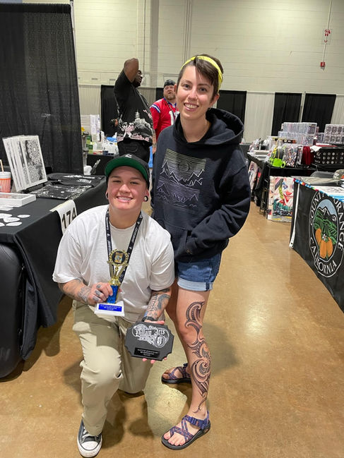 Lauren Tattoo posing with her client and their trophies that they won for the "Best Black Work/Tribal" category at the Villain Arts Tattoo Convention in Houston, Texas.
(Houston, Texas. 2022)