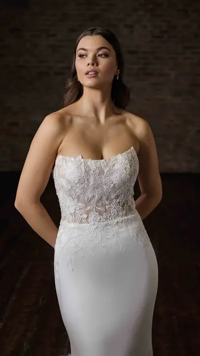 Close-up of Eddy K fit-n-flare wedding dress with a straight neckline and a strapless body on a bridal model posing in a studio.