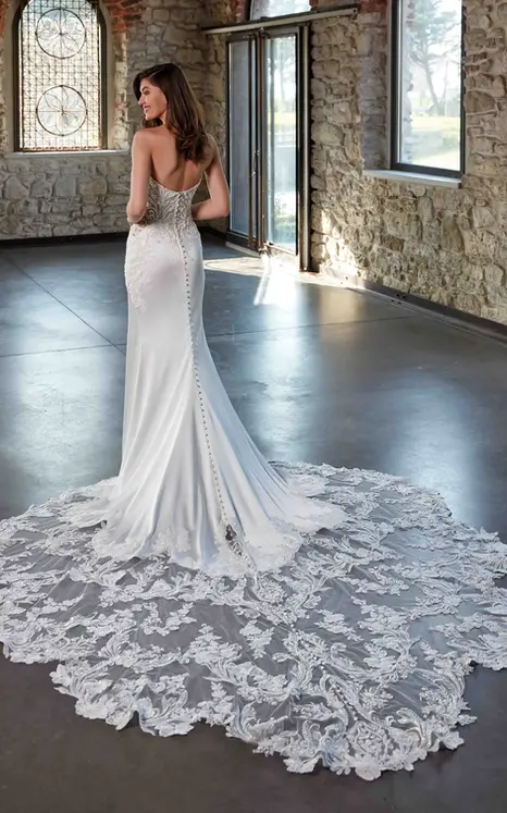 Back of Eddy K strapless fit-n-flare soft satin wedding dress with a stunning long train with lace details and scalloped edges on bridal model in warehouse