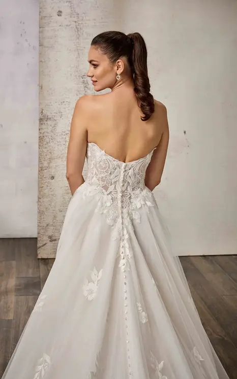 Back close of Eddy K lace ballgown wedding dress with a sweetheart neckline and a strapless bodice on a bridal model standing in an elegant studio.