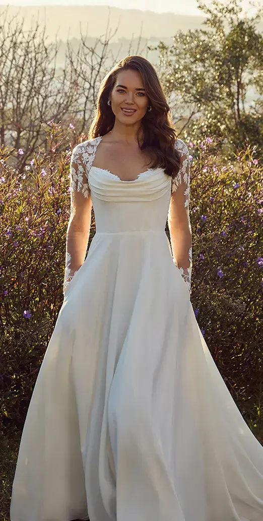 Blonde fair skinned woman sitting on white block wearing a multi coloured ballgown