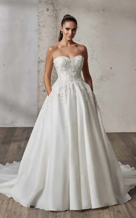 Eddy K Ball gown strapless wedding dress in organza with beaded silver embroidery with sequins on bridal model standing in studio