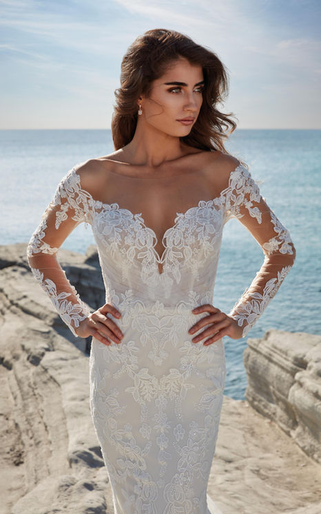 Woman wearing an Eddy K sweetheart neckline Fit-n-Flare wedding gown with long sleeves.