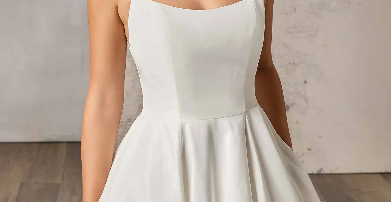 Close up of Eddy K taffeta ballgown wedding dress with a scoop neckline and a sleeveless body on a bridal model posing in a bridal studio.