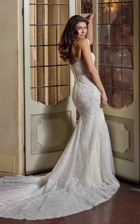 Back of of Eddy K tulle crepe fit-n-flare wedding dress with a straight neckline on a bridal model standing in an elegant room.
