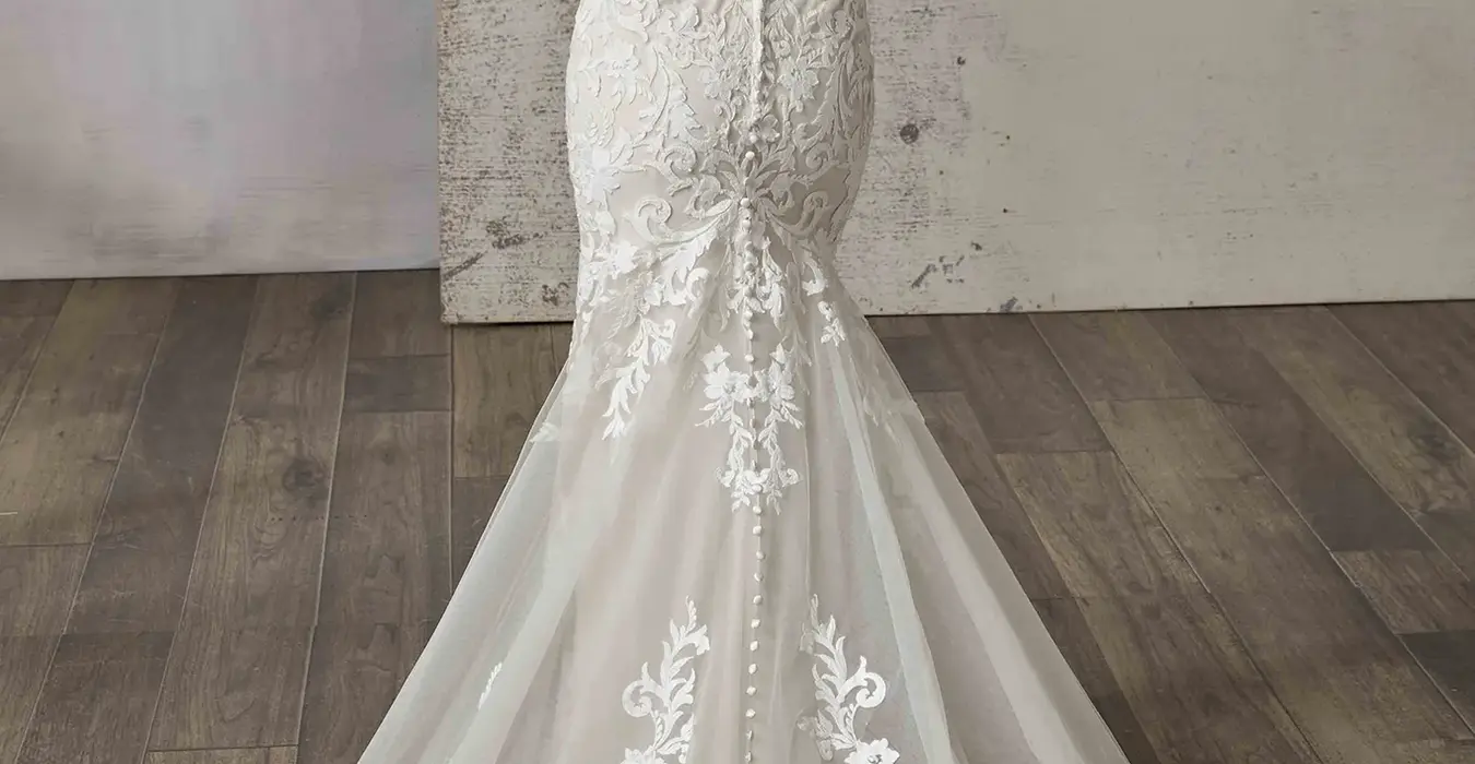 Back of Eddy K fit-n-flare all over lace wedding dress with scoop unlined back on bridal model standing in studio.