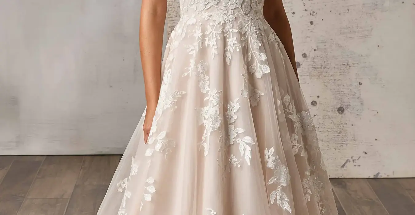 Eddy K lace ballgown wedding dress with a v-neck neckline and a sleeveless body on a bridal model posing in a studio.