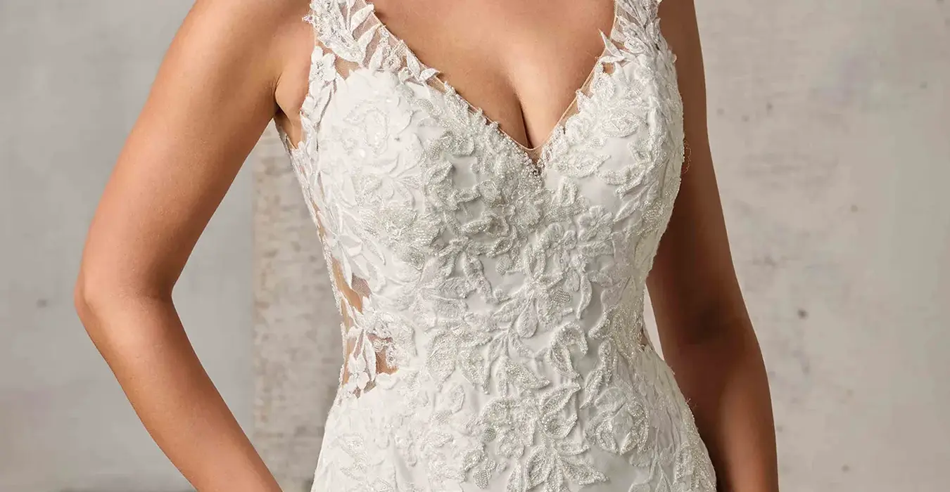 Close up of Eddy K crêpe fit-n-flare wedding dress with a v-neck neckline and a sleeveless body on a bridal model posing in a studio.