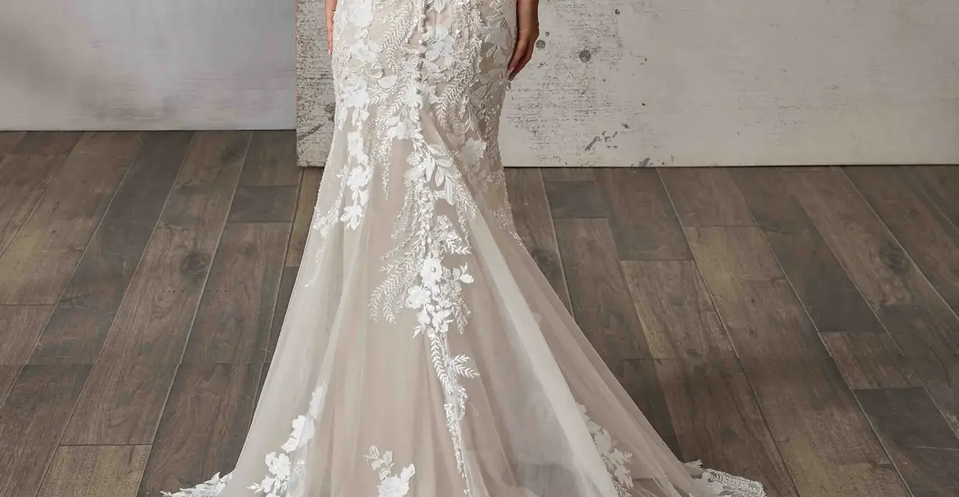Back of Eddy K lace and tulle fit-n-flare wedding dress with spaghetti straps and train with scalloped edges on bridal model in studio.