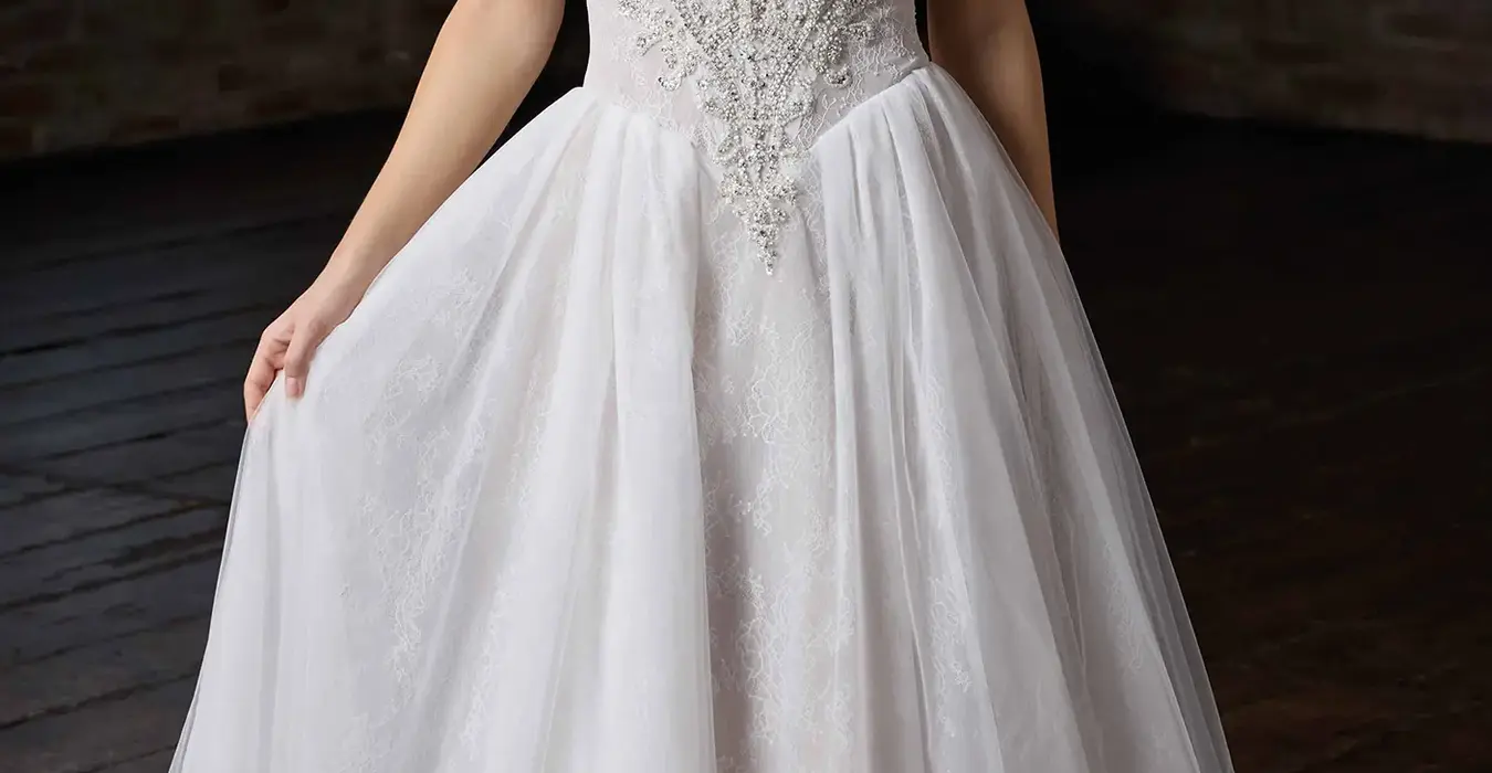 Eddy K ballgown wedding dress with a straight neckline and a strapless body on a bridal model posing in a studio.