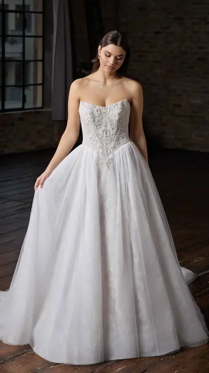 Eddy K ballgown wedding dress with a straight neckline and a strapless body on a bridal model posing in a studio.