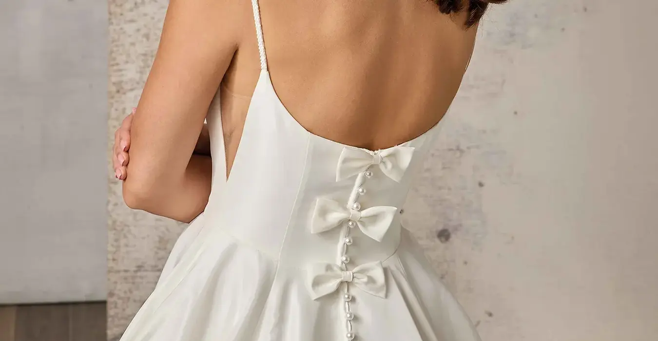 Close up back of Eddy K taffeta ballgown wedding dress with a scoop neckline and a sleeveless body on a bridal model posing in a bridal studio.