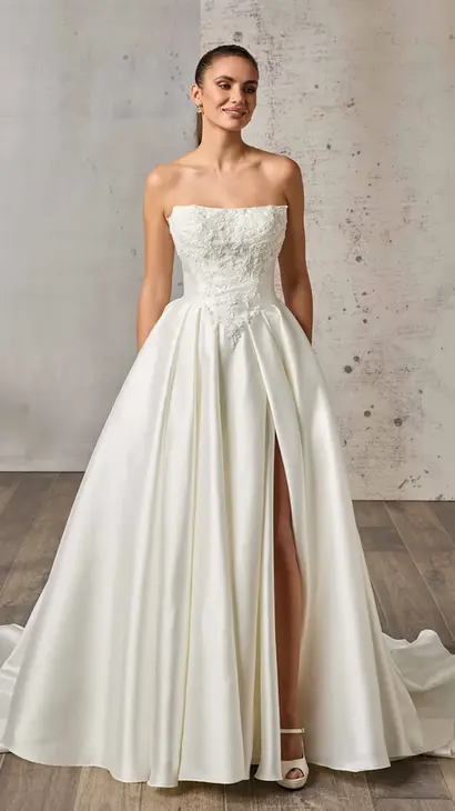 Eddy K mikado ballgown wedding dress with a straight neckline and a strapless body on a bridal model posing in a bridal studio