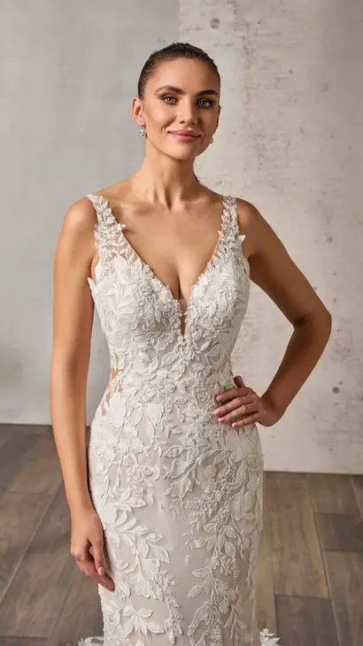 Close up of Eddy K lace and tulle fit-n-flare wedding dress with a v-neck neckline and a sleeveless body on a bridal model standing in a bridal studio.