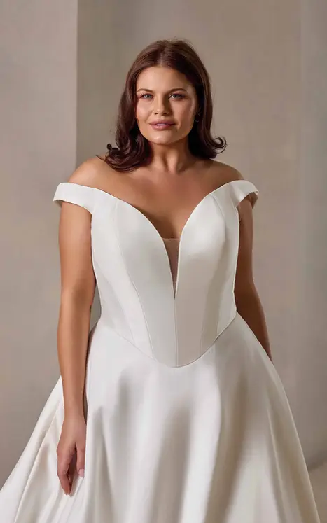Close up of Eddy K mikado ballgown wedding dress with a v-neck neckline and elegant off-shoulder Mikado straps on a bridal model standing in an elegant studio.