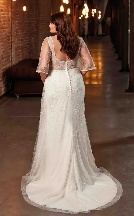 Back of Eddy K tulle sheath wedding dress with sand lining and flutter sleeves on bridal model with hair down