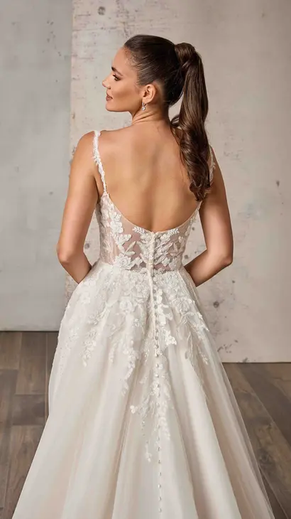 Close up back of Eddy K lace mermaid wedding dress with a v-neck neckline and a sleeveless body on a bridal model posing in studio.