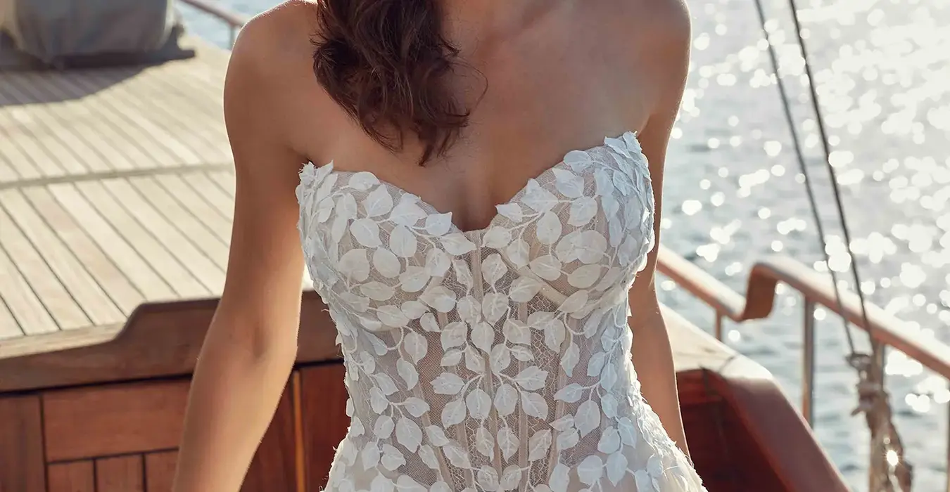 Sleeveless wedding gown by Italian wedding dress designer Eddy K with a sweetheart neckline and floral appliqués from the neckline to the train
