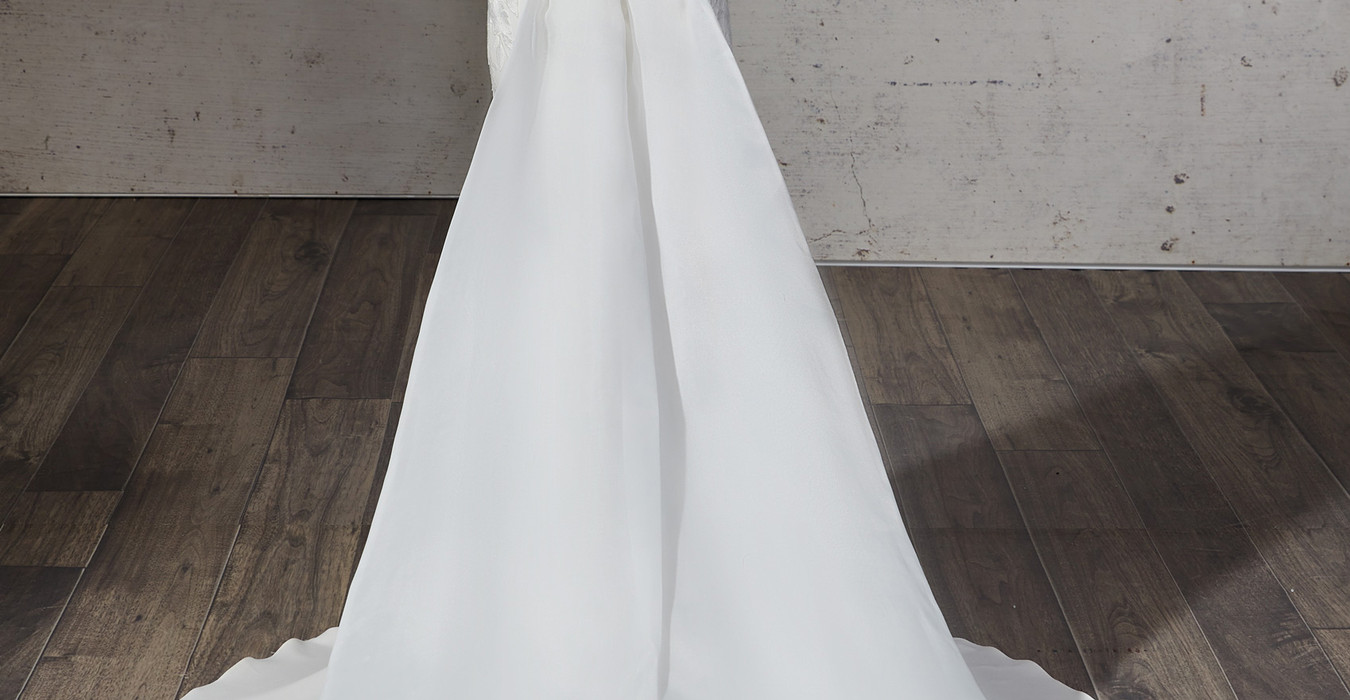 Back of Eddy K Crepe mermaid wedding gown with split train on blonde model with pony tail.