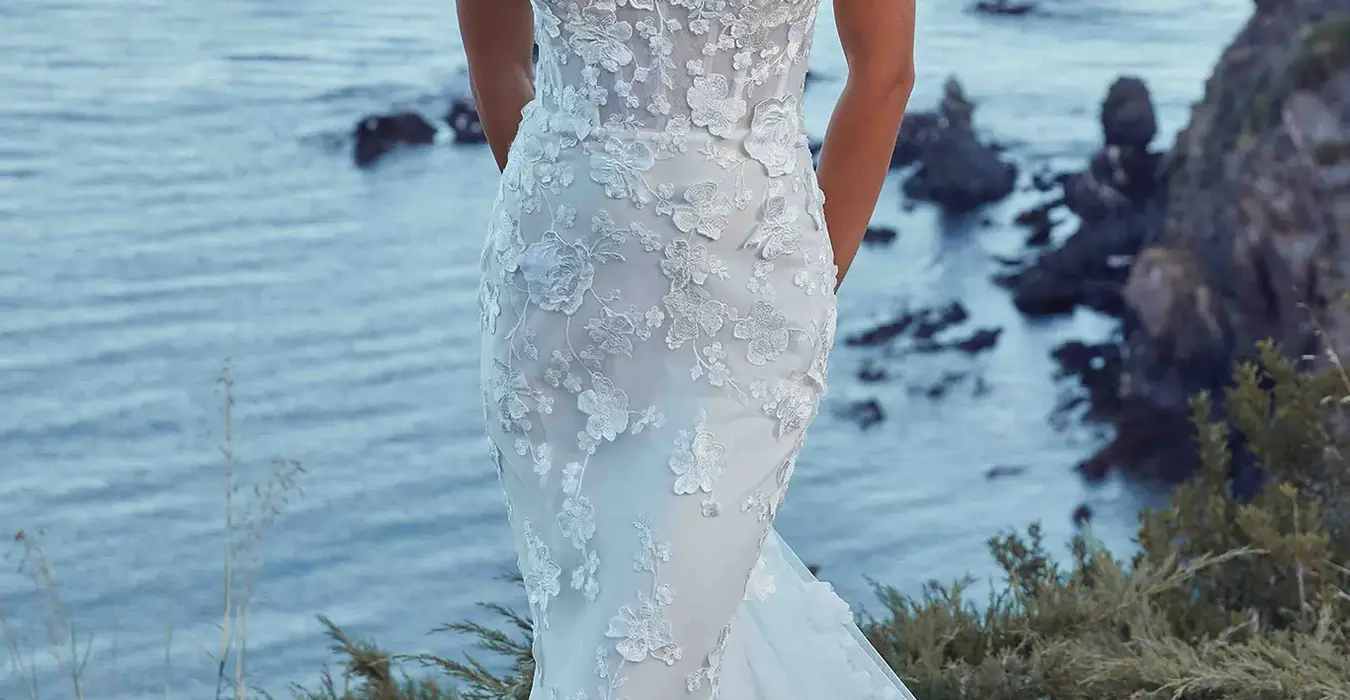 Eddy K strapless fit-n-flare wedding gown with ivory lace over ivory tulle, unlined Chantilly lace  bodice on bridal model standing near the beach.