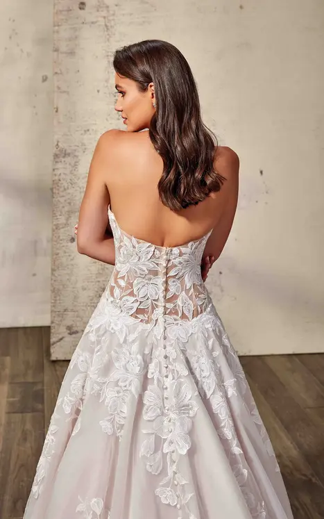 back of bride wearing wedding ballgown by wedding dress designer Eddy K with ivory lace and minimal beading over ivory tulle, lavender tulle & matte lining, unlined skin bodice, lavender buttons to end of train and drop waist. She is photograph in a beautiful modern studio.