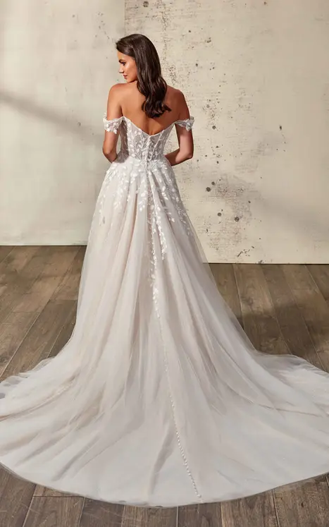 Back of Eddy K lace and tulle ballgown with 3D chiffon appliques, off-shoulder straps and buttons to end of train. Wedding dress is worn by bridal model standing in studio with hair down.